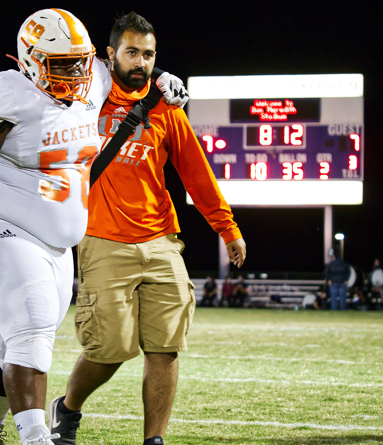 Mineola sports trainer Justin Rivers helps Yellowjacket Kejuan Fite off the field in a recent game against Mt. Vernon.